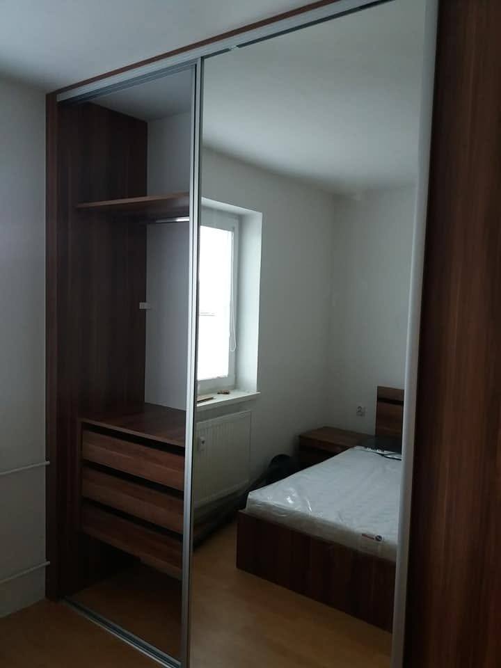Kleiderkasten in Nussbaum-Dekor mit Spiegel und offenem Innenraum mit Laden.