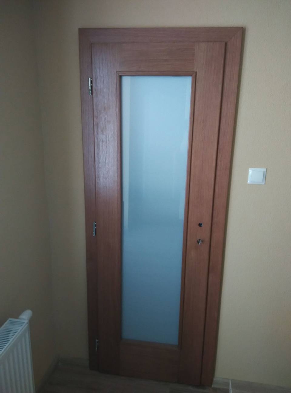 Orechové dvere s celoplošnou výplňou z matného skla pri radiátore