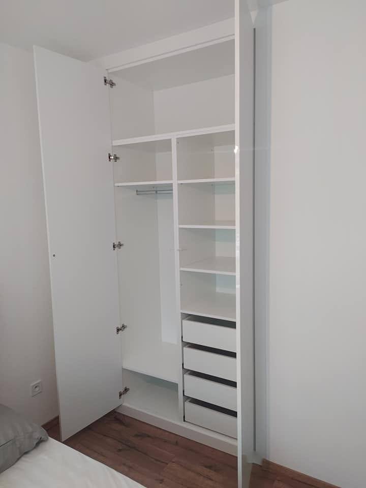 Geöffneter weißer Kasten mit Fachböden, Kleiderstange und Ladenblock.