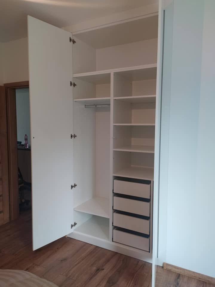 Geöffneter weißer Kasten mit Laden, Fachböden und Kleiderstange.