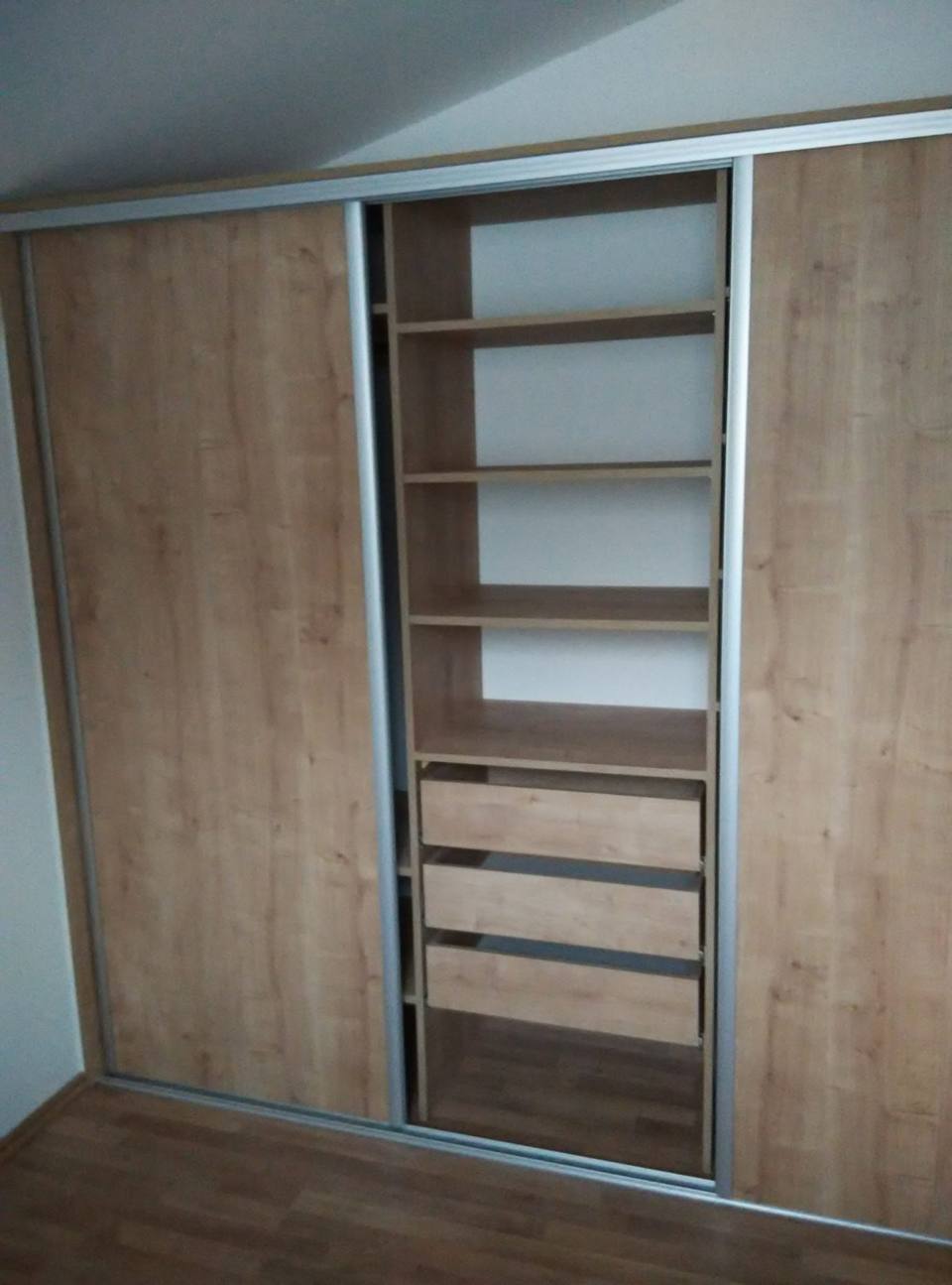 Geöffneter Schiebetürkasten in Eichendekor mit Fachböden und weißen Laden.