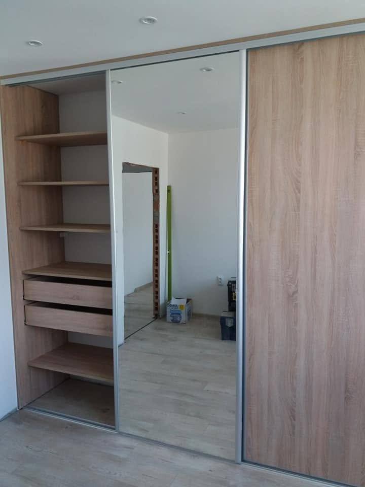 Geöffneter Schiebetürkasten in Eichendekor mit Spiegel, Fachböden und Laden.