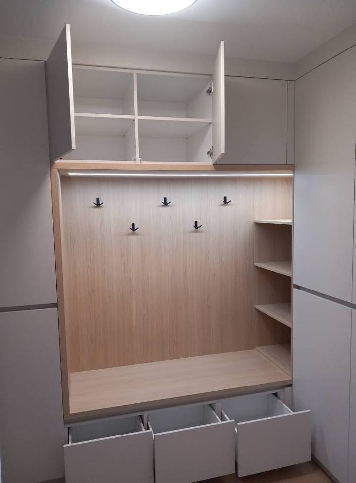Offene Garderobennische in Eichendekor mit weißen Kästen und Stoffkörben.