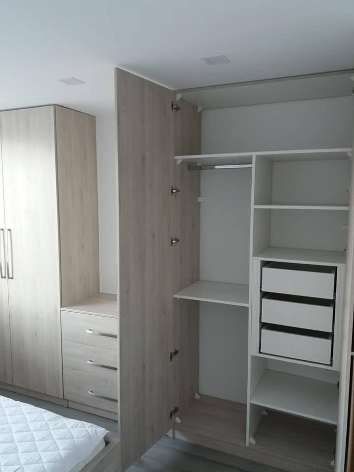 Geöffneter Kleiderschrank mit weißem Innenraum im Schlafzimmer