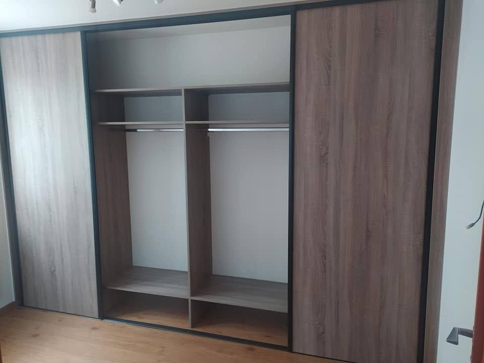 Geöffneter Schrank in graubraunem Dekor mit Kleiderstange