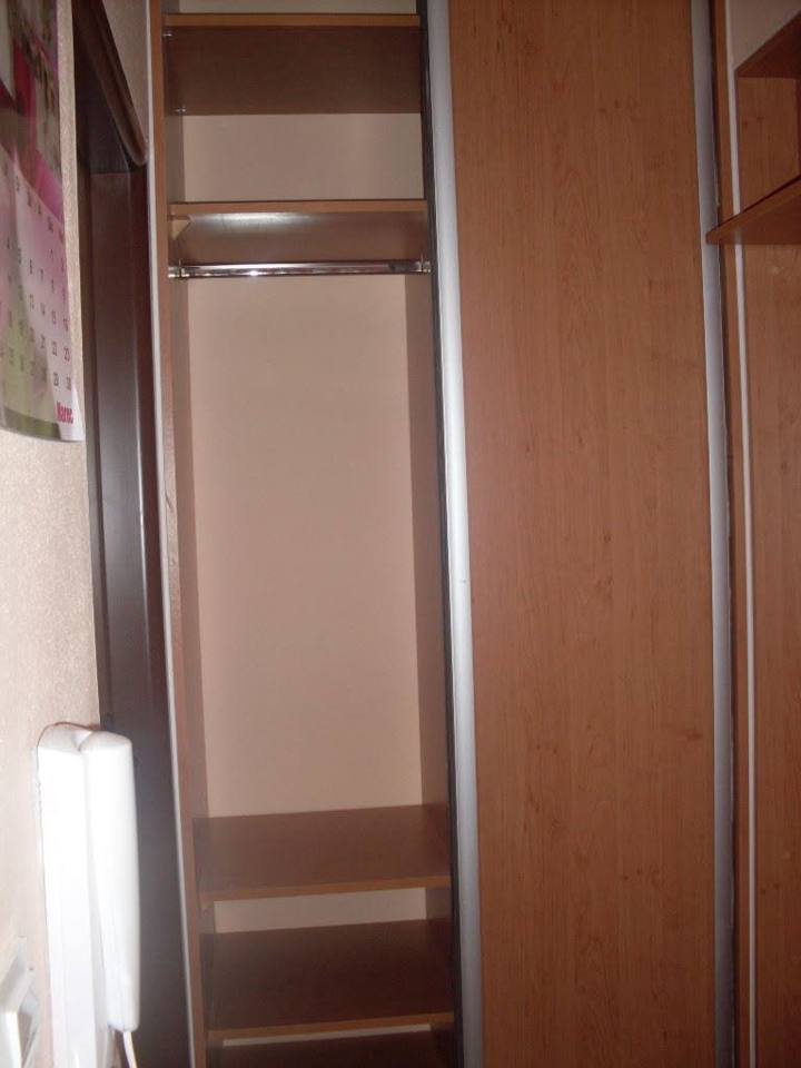 Geöffneter Einbaukasten mit Kleiderstange in Kirschdekor.