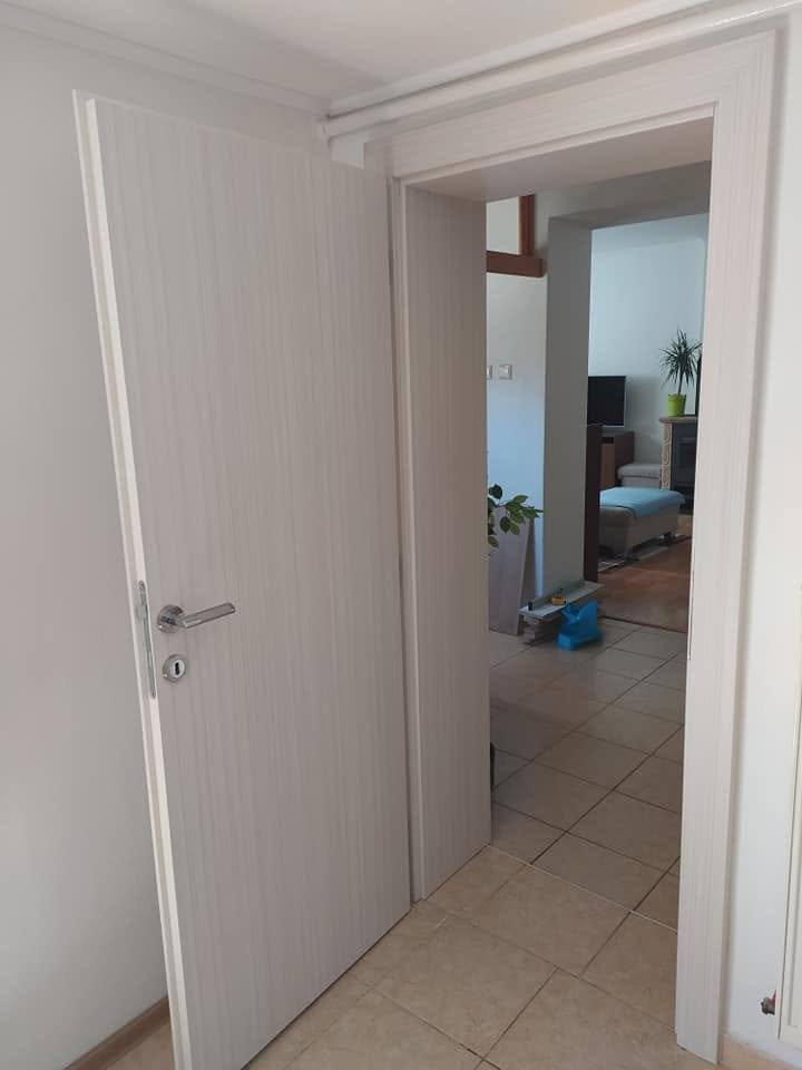 Offene Tür in gebleichtem Dekor, die vom Flur ins Wohnzimmer führt.