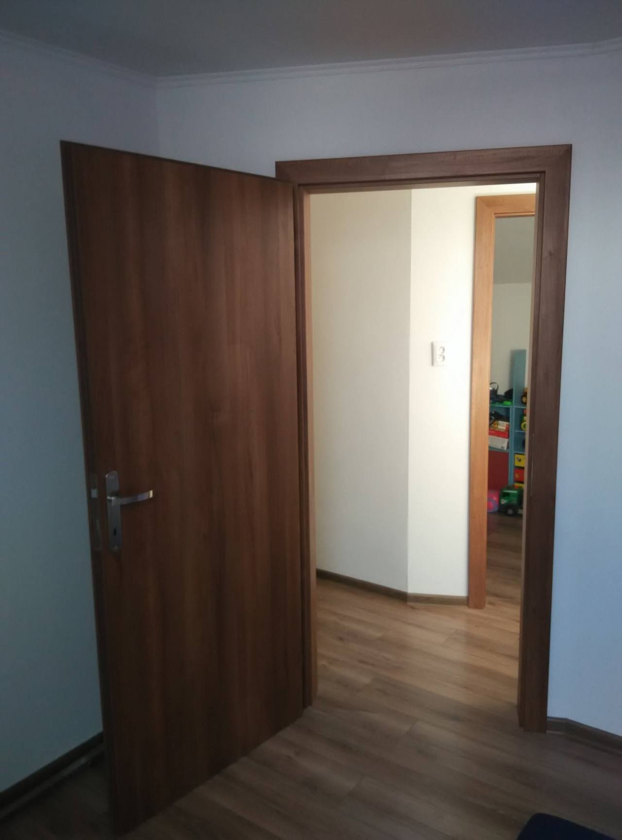 Pootvorené orechové dvere s obložkovou zárubňou vo svetlej chodbe