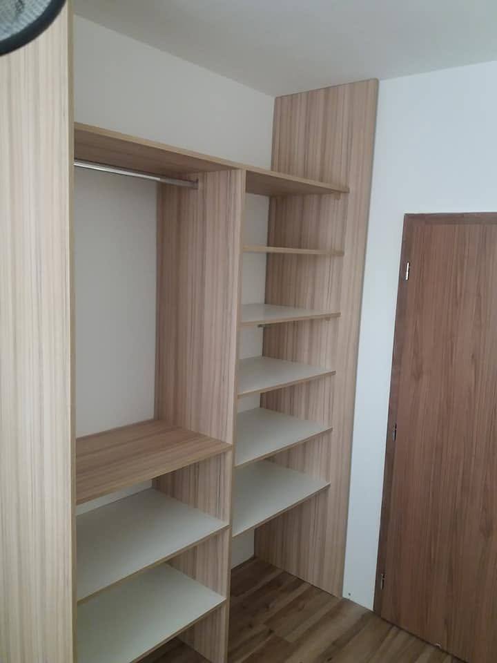 Offener Kleiderkasten in Eichendekor mit weißen Fachböden und Kleiderstange.