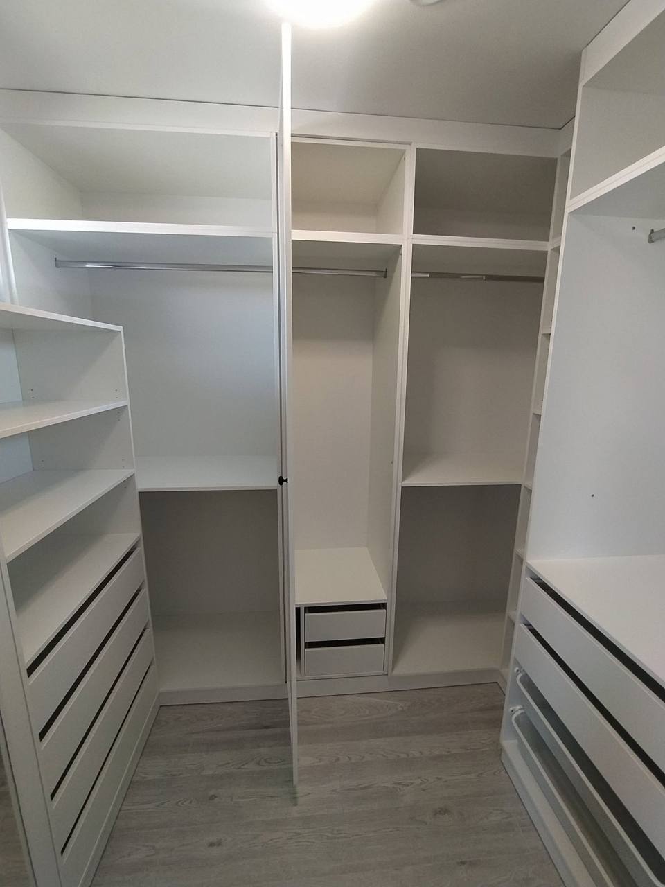 Weißes Ankleidezimmer mit Borden, Laden und Kleiderstange