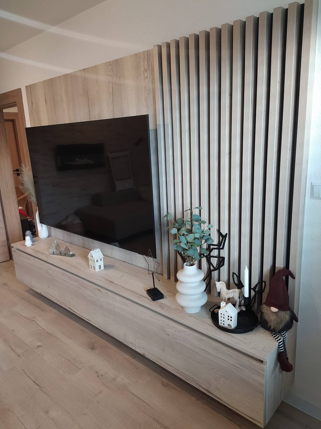 Eichen-TV-Wand mit schwarzen Lamellen und niedrigem grauem Möbel