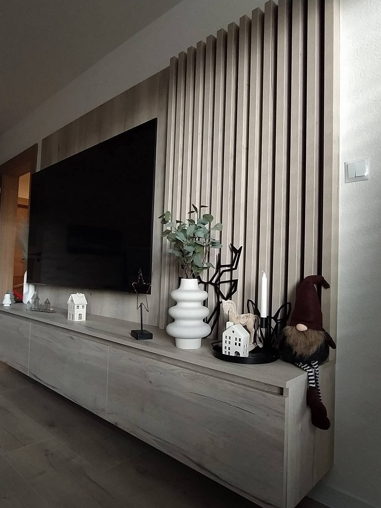 TV-Wand mit Eichenverkleidung, schwarzen Lamellen und grauem Möbel