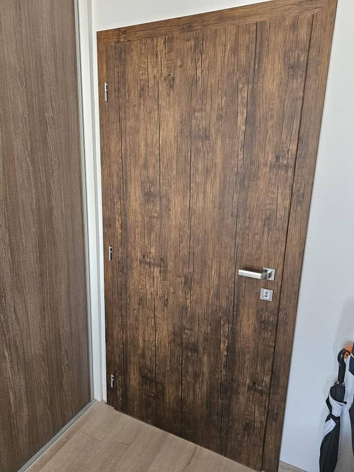 Massive Tür in dunklem Altholz-Eiche-Dekor mit kräftiger Maserung.