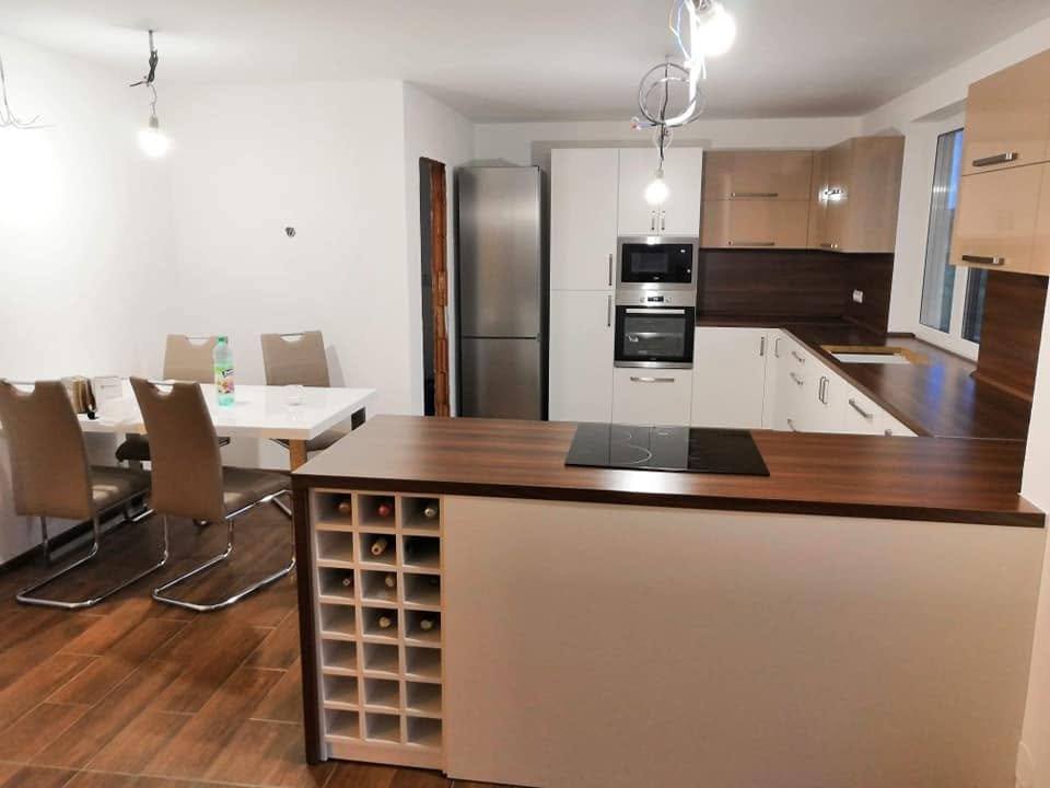 Weiße Küche mit Halbinsel, Weinregal und Esstisch im Hintergrund