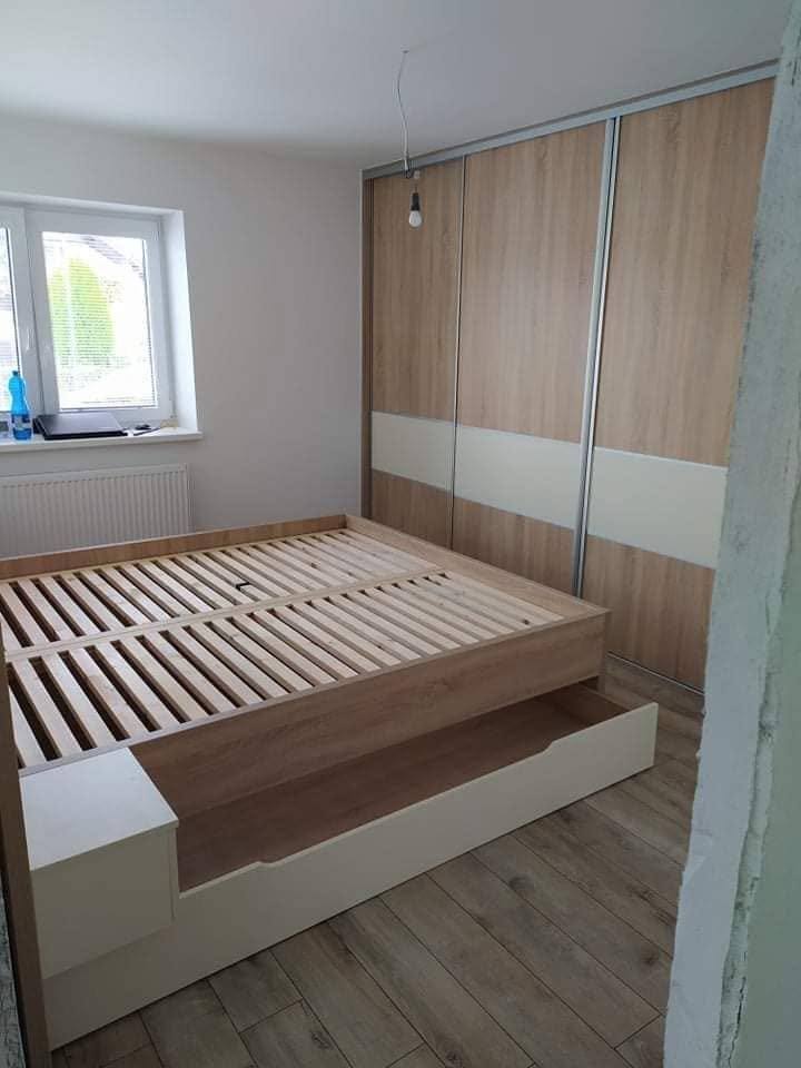 Bett mit Lade im Zimmer mit Schwebetürenkasten am Fenster
