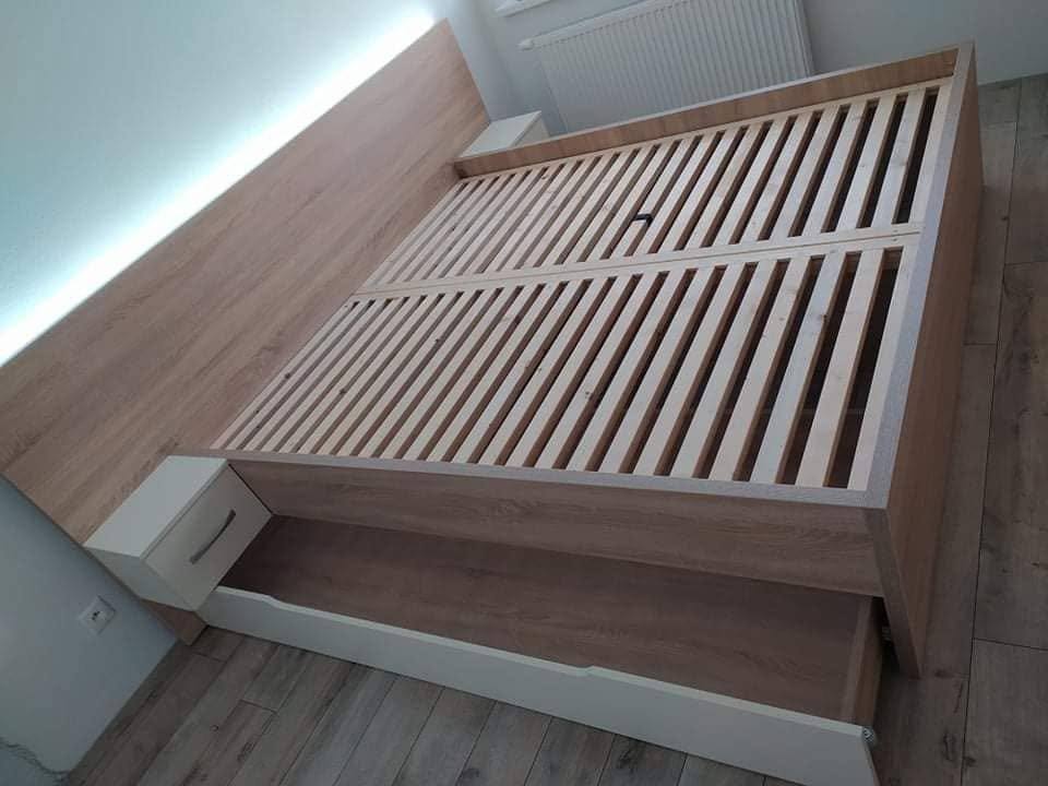 Bett mit beleuchtetem Kopfteil und weißer Lade am Fußende