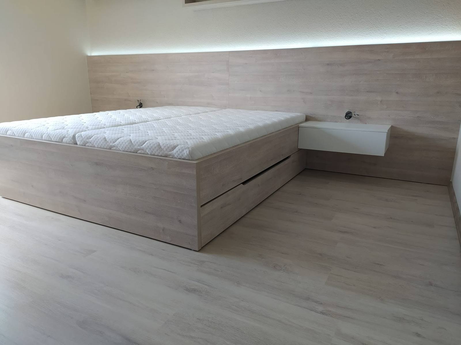 Bett in hellem Eichendekor mit Laden und beleuchteter Verkleidung