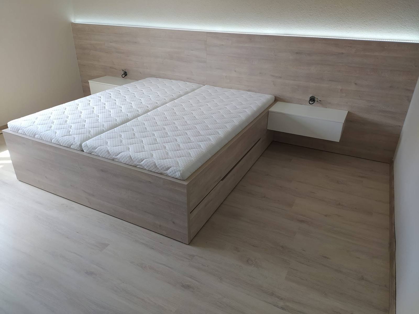 Doppelbett mit LED-Wandverkleidung und weißen Nachtkästchen