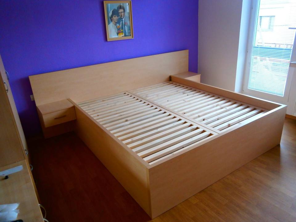 Bett in Buchendekor mit integrierten Nachtkästchen vor violetter Wand