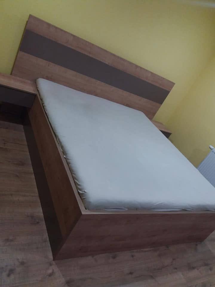 Doppelbett in Eichendekor mit anthrazitem Band vor gelber Wand