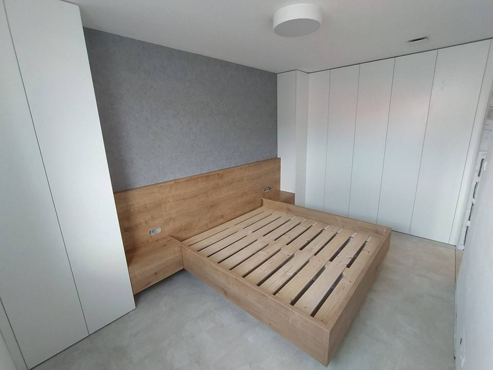 Bett in Eichendekor mit Wandpaneel zwischen weißen Einbaukästen
