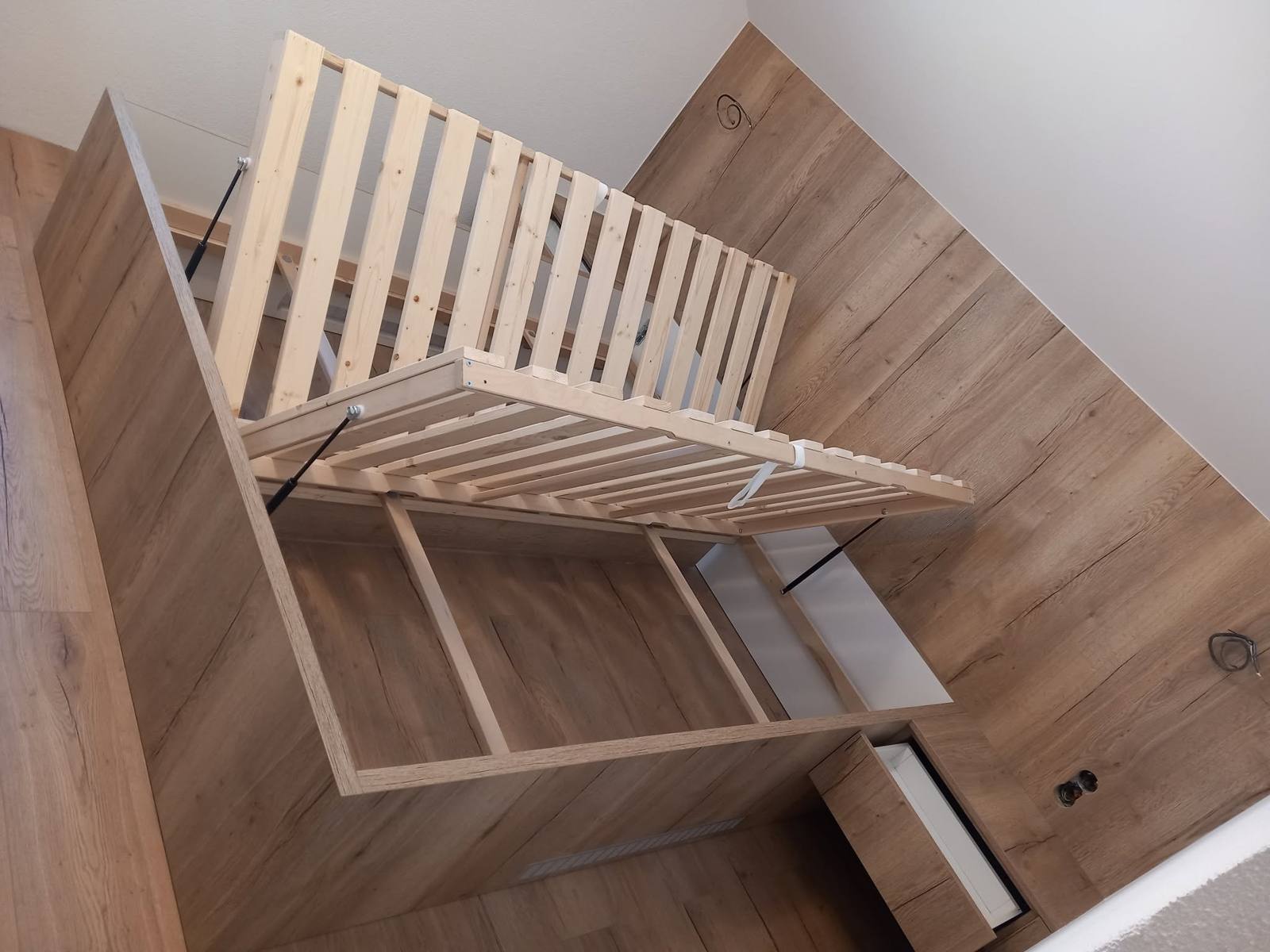Draufsicht auf hochgeklappte Lattenroste und den Stauraum im Bett