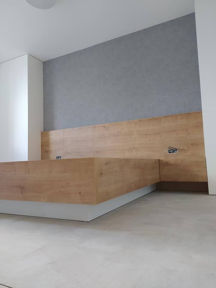 Bett in Eichendekor mit breitem Kopfteil vor grauer Tapete