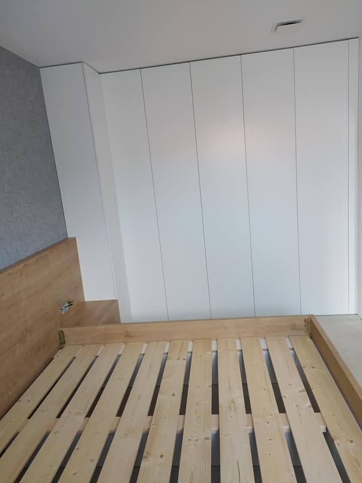 Lamelový rošt postele a biela skriňa do stropu bez úchytiek
