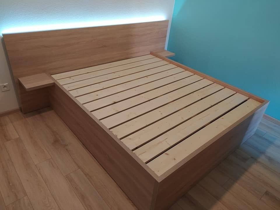 Bett in Eichendekor mit beleuchtetem Kopfteil vor türkiser Wand