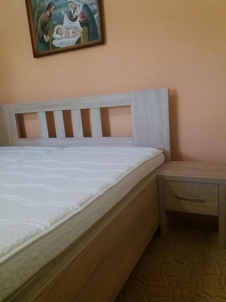 Bett in grauem Eichendekor mit Ausschnitten im Kopfteil und Nachtkästchen