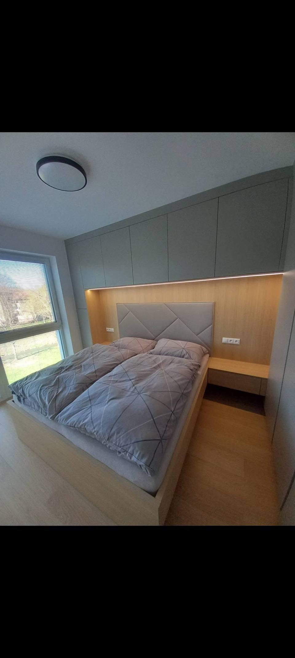 Bett in Eichennische mit LED-Streifen zwischen grauen Kästen