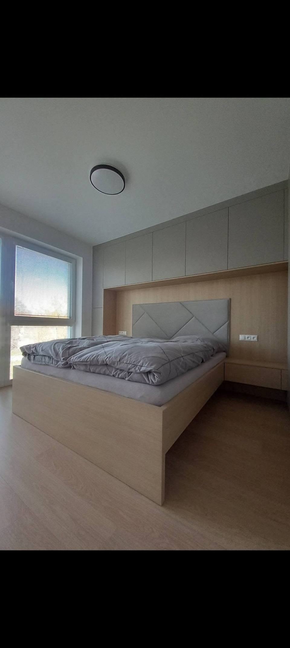 Schlafzimmer mit Bett, Eichenverkleidung und Polsterkopfteil beim Fenster