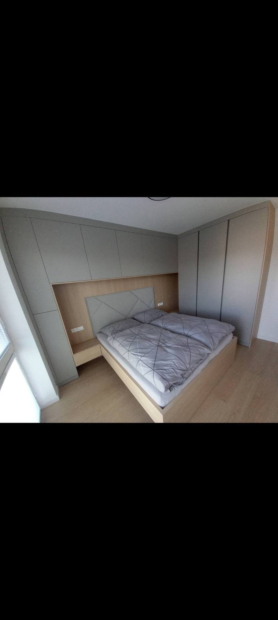 Schlafzimmer mit beleuchteter Verkleidung hinter dem Bett und grauen Kästen