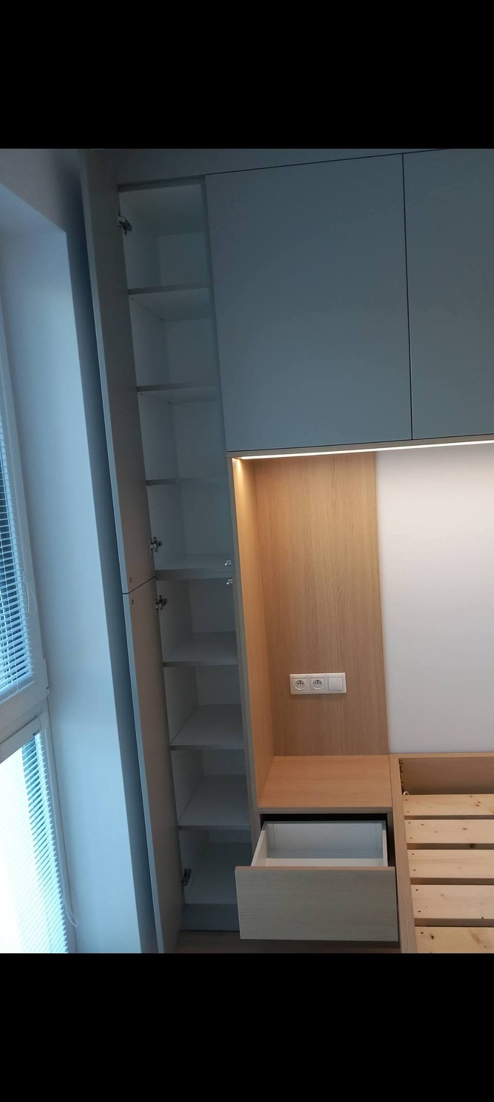Herausgezogene Lade unter dem Nachtkästchen neben grauem Kasten