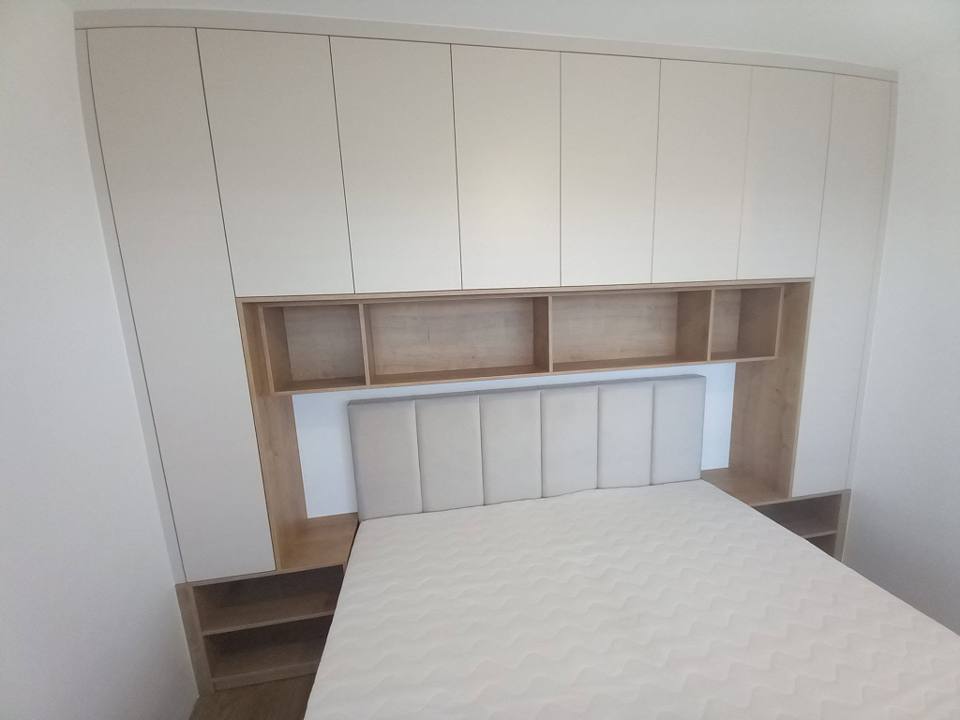 Bett mit Polsterkopfteil, eingebaut in eine helle Kastenwand