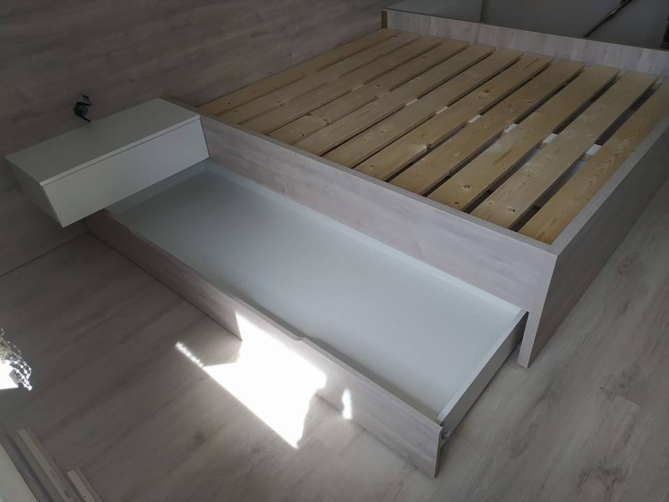 Bett in hellem Dekor mit herausgezogener weißer Lade und Nachtkästchen