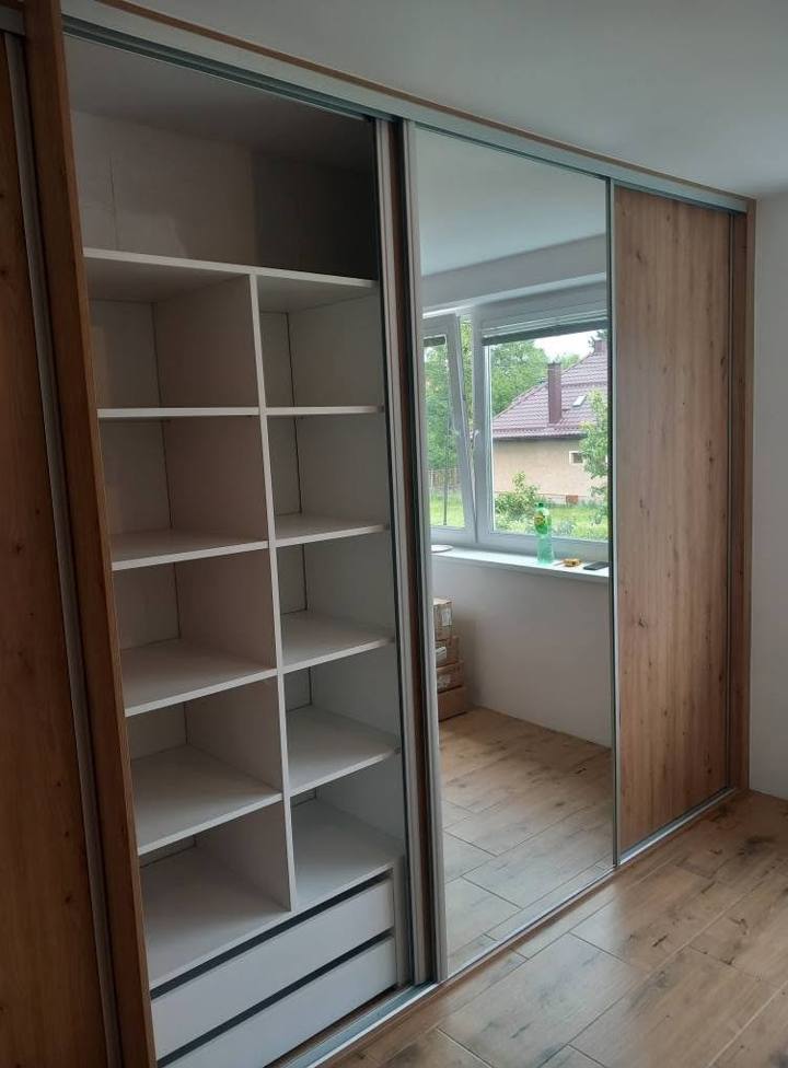 Geöffnete Eichentür gibt weiße Fächer und Laden beim Fenster frei