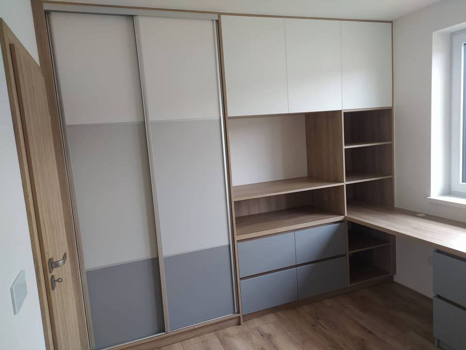Weißer Schwebetürenkasten mit grauen Feldern und angrenzendem Schreibtisch