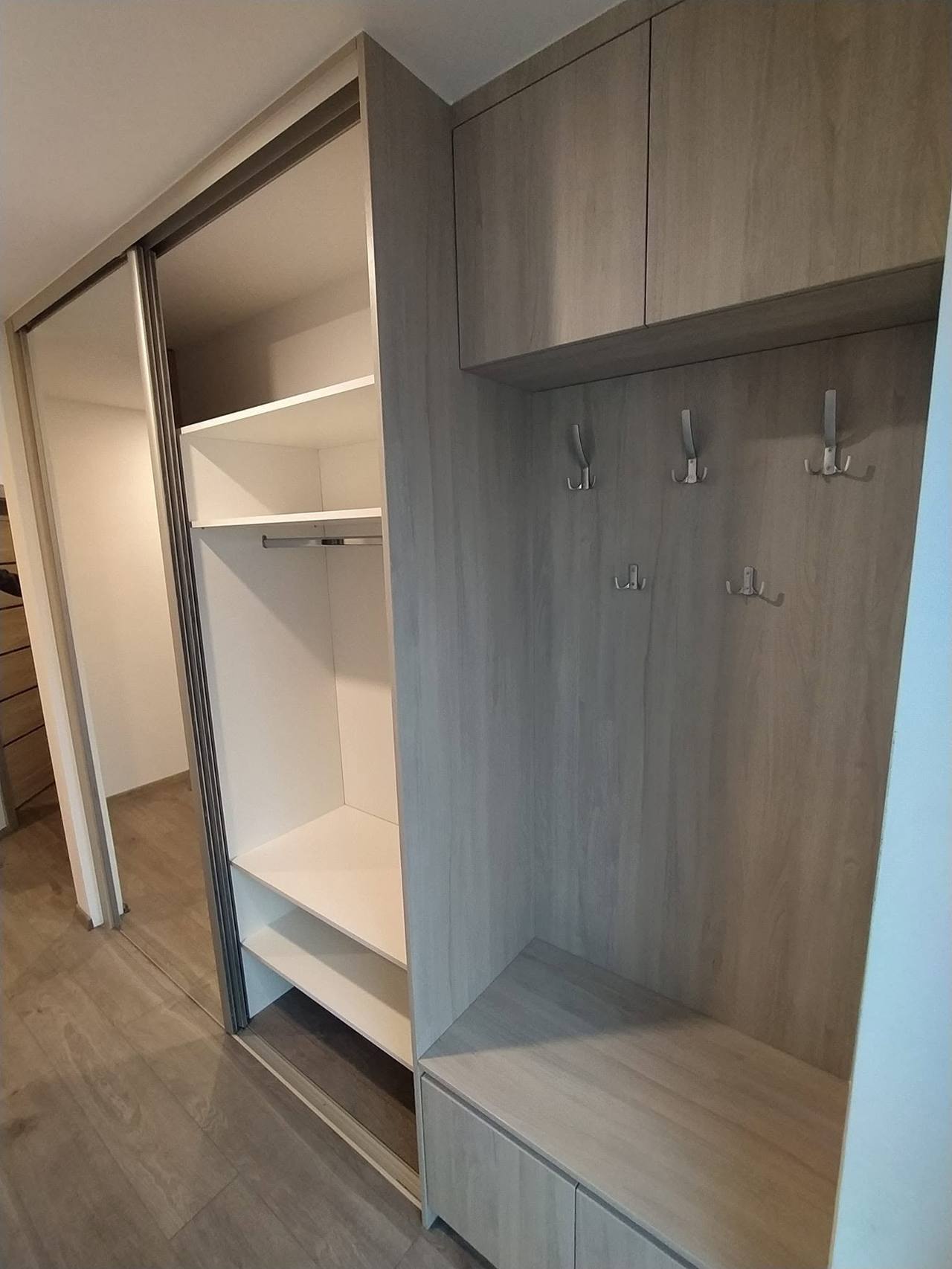 Schiebetürenkasten in Grau-Eiche-Dekor mit offenem Seitenteil mit Haken und Fächern.