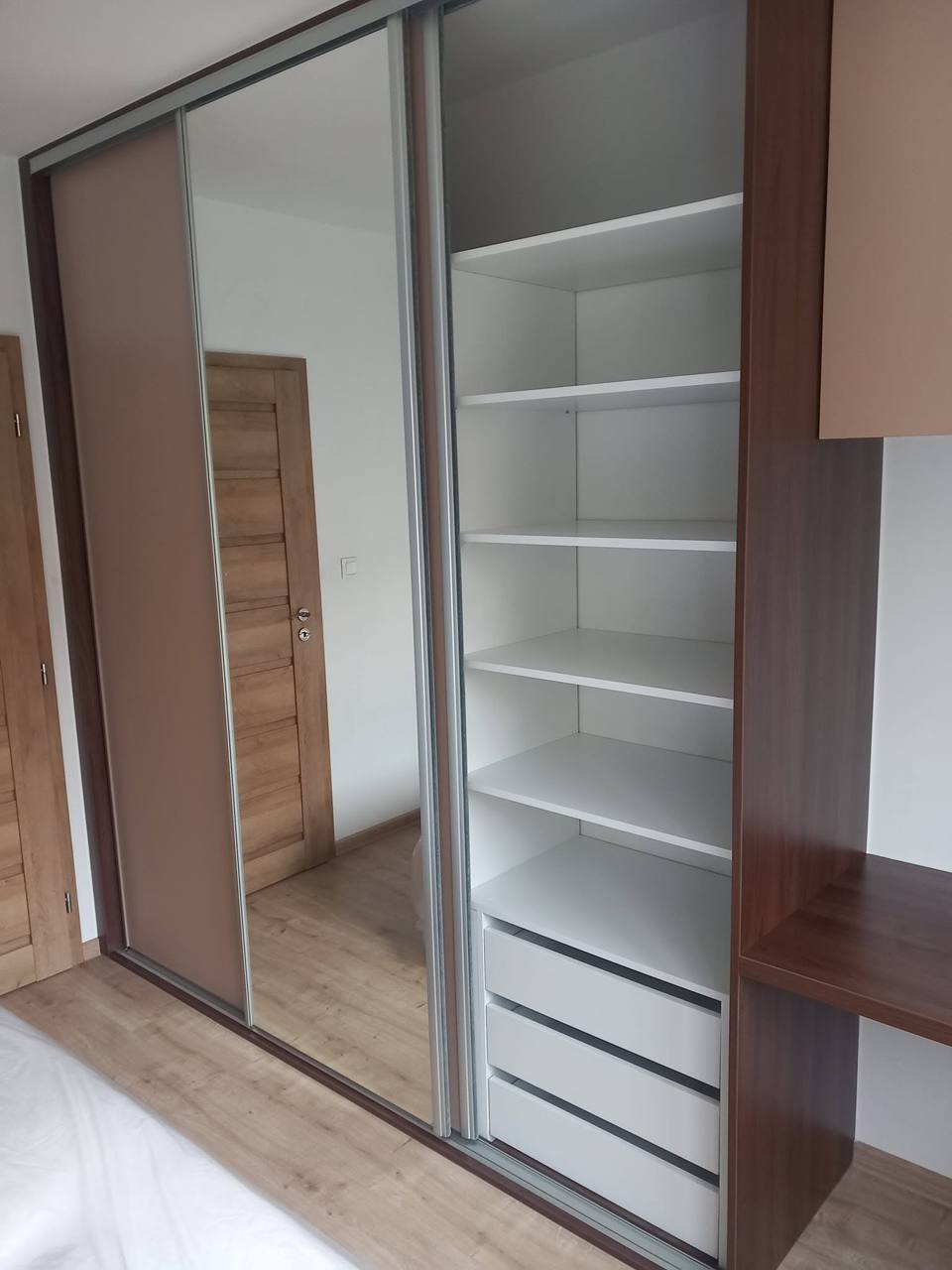 Geöffneter Kasten mit Spiegel, Fachböden und Laden im Schlafzimmer