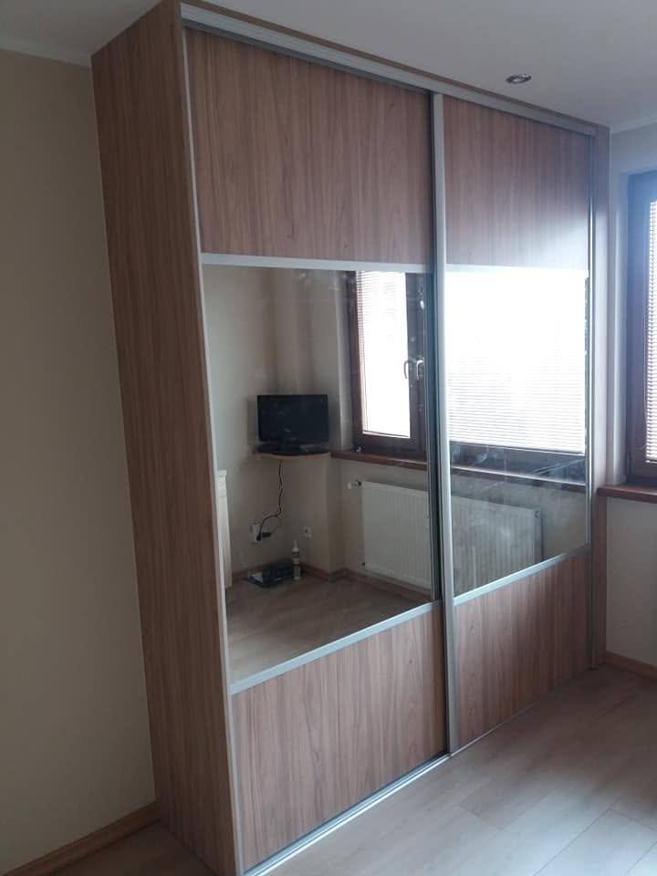 Schiebetürenkasten mit zwei Spiegeln in braunem Holzdekor beim Fenster