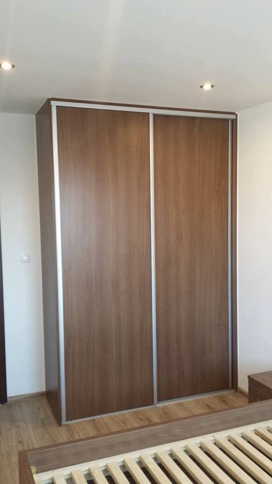 Posuvná skriňa v orechovom dekore pri stene v spálni.