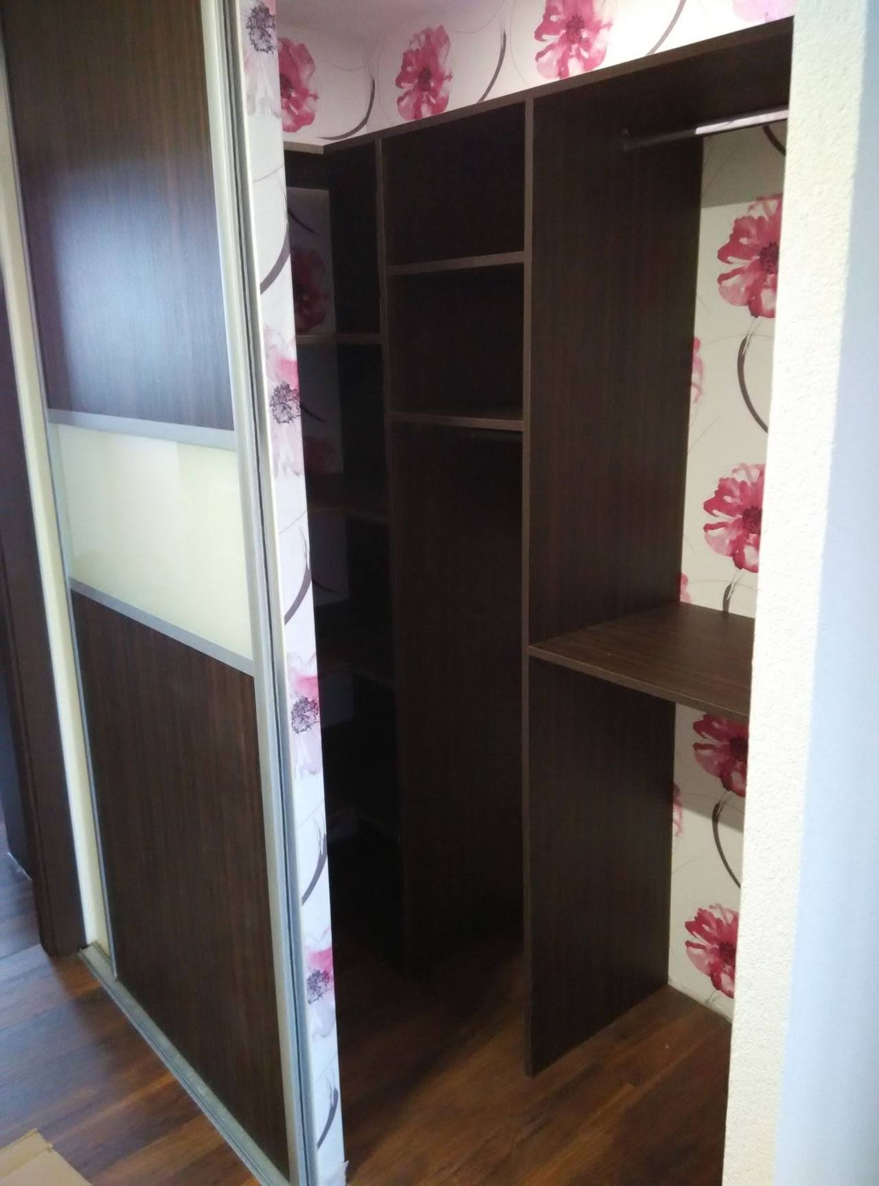 Geöffnete Wenge-Tür gibt dunkle Fachböden und eine Ablageplatte frei