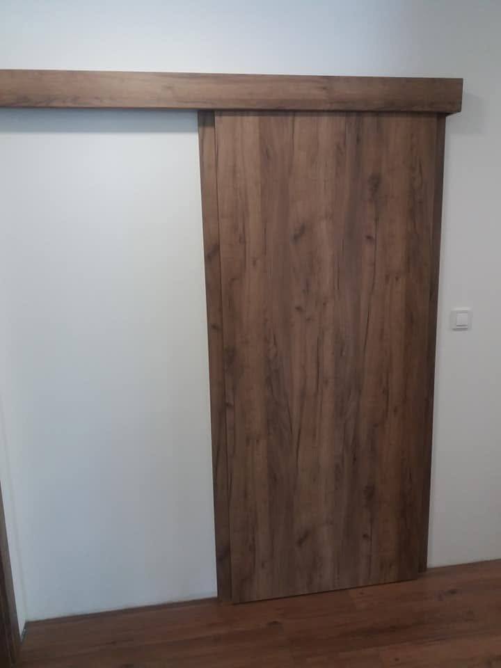 Posuvné orechové dvere vedené po stene nad otvorom