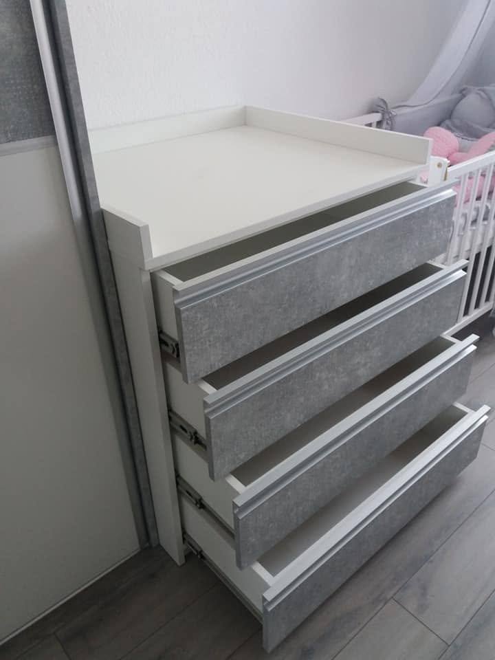 Wickelkommode mit herausgezogenen Laden neben dem Gitterbett