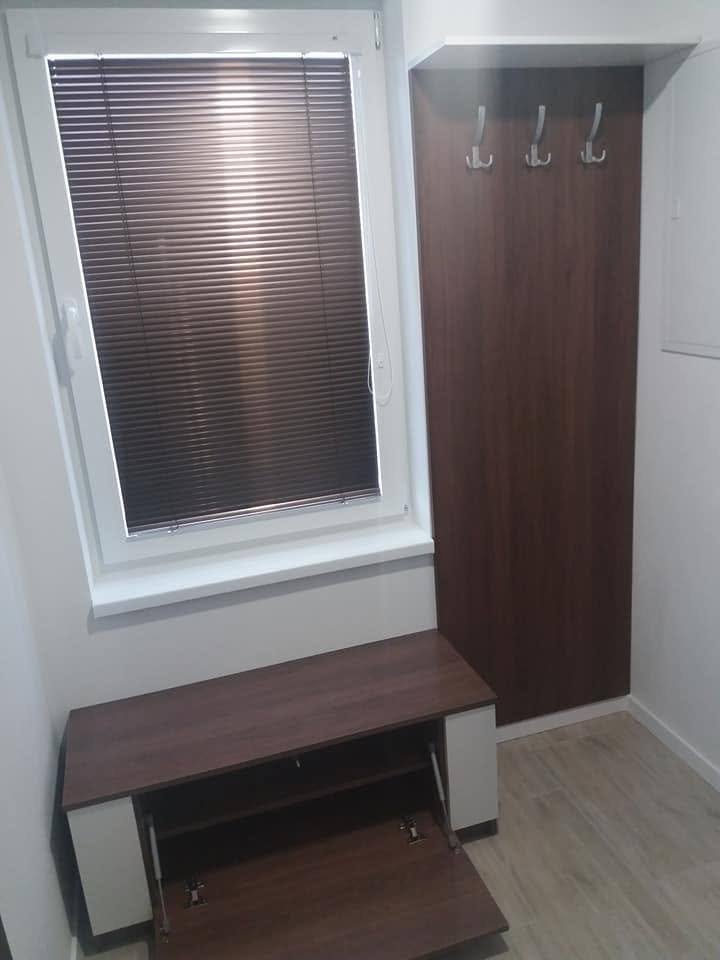 Vorzimmer mit Nussbaum-Garderobenpaneel und niedrigem Schuhschrank beim Fenster