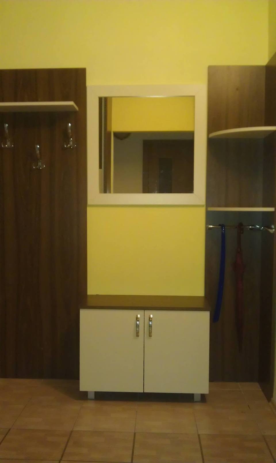 Dunkles Garderobenpaneel, Spiegel und niedriges Kästchen an gelber Wand