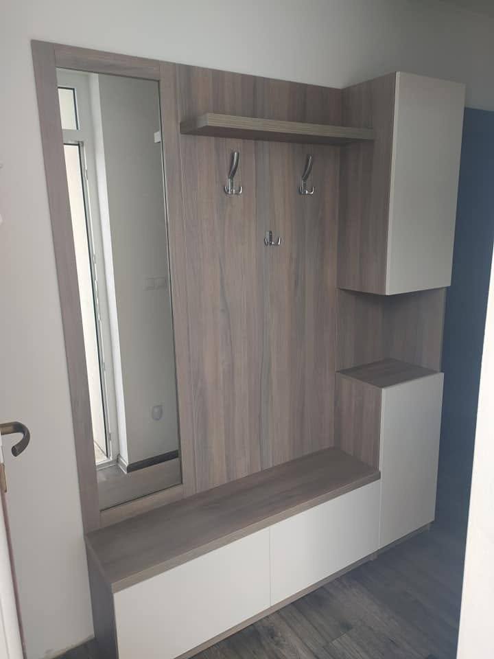 Kleiderstange mit Haken über einer weißen Sitzbank mit Stauraum im Vorzimmer.