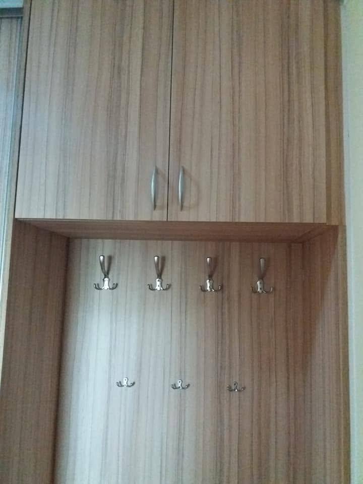 Vorzimmernische mit Oberschranktüren in Eichendekor und vier Metallhaken.