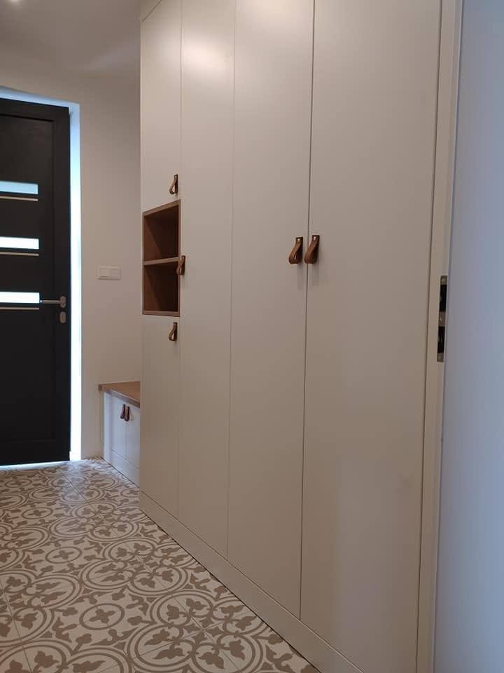 Kastenwand mit Ledergriffen entlang des Vorzimmers mit Musterfliesen